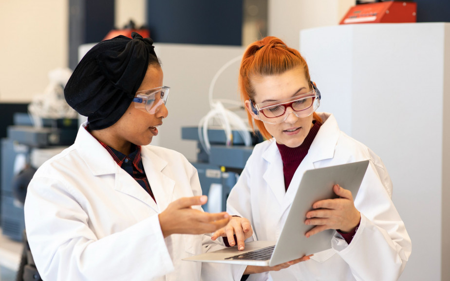 Two women in a laboratory check a computer