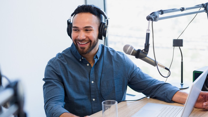 Man is in a recording studio in front of a microphone recording a podcast