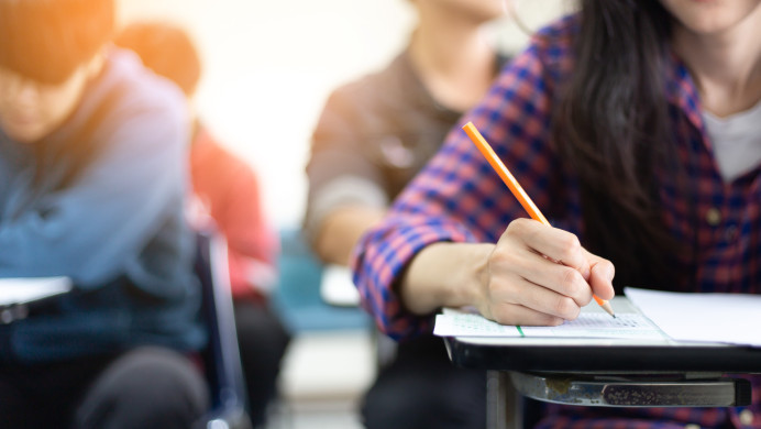 Student sitting an NCEA exam paper, writing answers in their answer papers