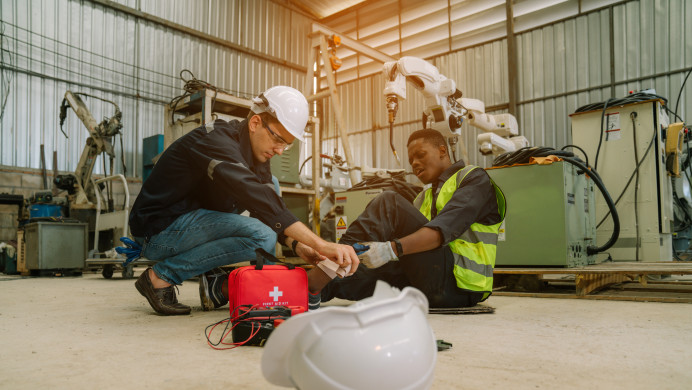 A worker giving first aid to their injured workmate